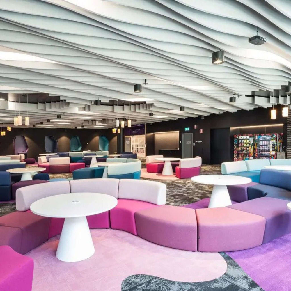 Modern lounge area featuring colorful seating and acoustic ceiling design for enhanced sound absorption and aesthetics.