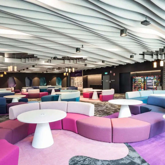 Modern lounge area featuring colorful seating and acoustic ceiling design for enhanced sound absorption and aesthetics.